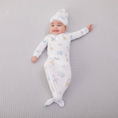 Kūdikis aprengtas balto smėlinuko ir kepurėlės komplektu su gyvūnėliais: žirafomis, drambliukais, zebriukais ir paukščiukais