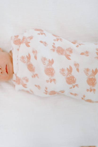 Ant lovos gulintis naujagimis įsuktas į baltos spalvos su rausvomis rožytėmis smėlinuką. Modelis Rosettes