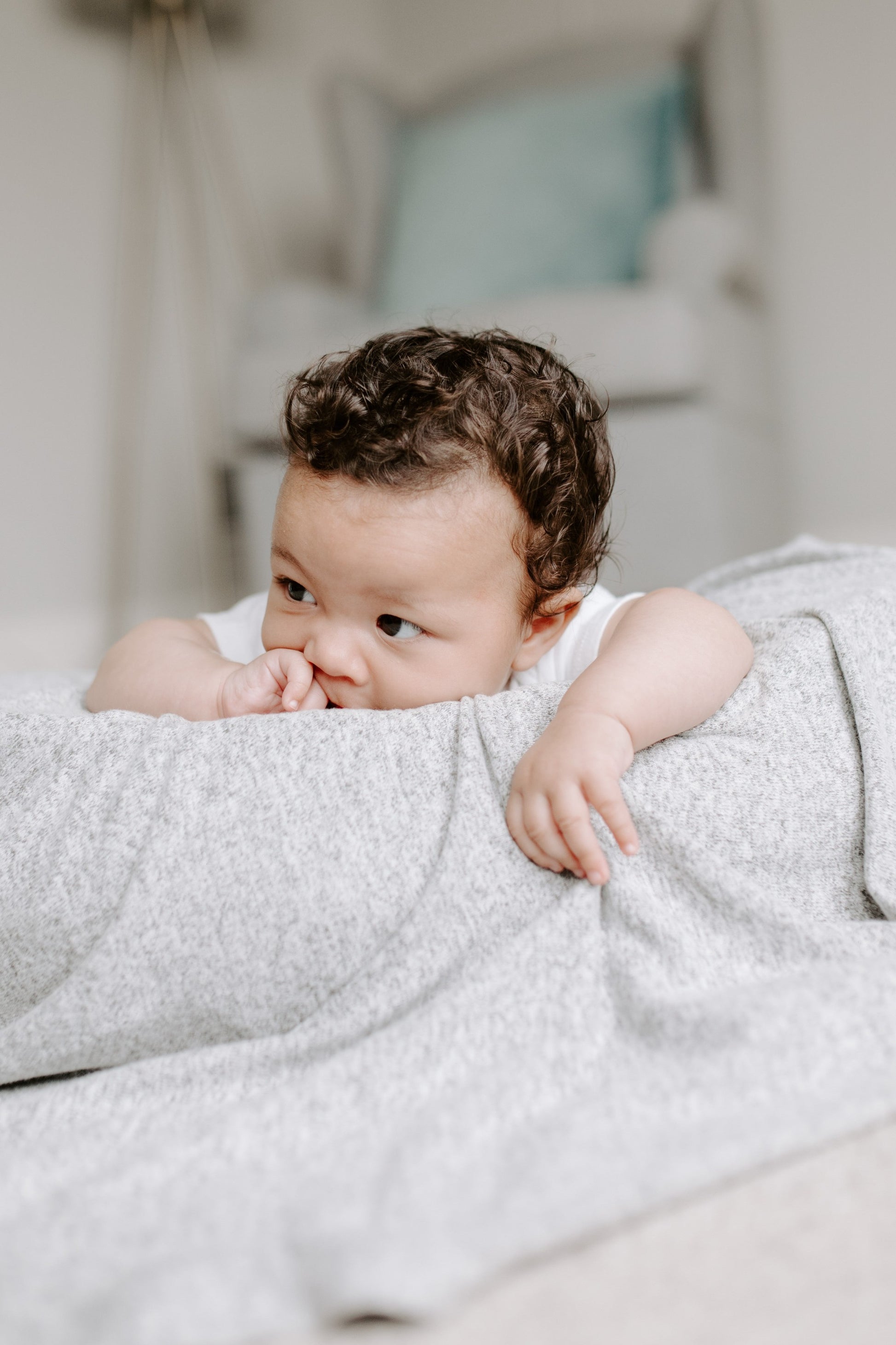 Naujagimis gulintis ant itin švelnaus ir kokybiško pilkos spalvos smėlinuko jaukiame,šviesiame kambaryje.Modelis Heather Grey